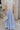 Back view of female model wearing the Alana Periwinkle Tiered Maxi Skirt which features Periwinkle Lightweight Fabric, Maxi Length, Periwinkle Thigh Length Lining, Tiered Body and Elastic Waistband with Drawstring Ties