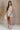 Full body view of female model wearing the Elodie Beige Ruffle Tier Sleeveless Romper which features Beige Lightweight Fabric, Beige Lining, Ruffle Tier Details, Round Neckline, Sleeveless and Back Button Closure
