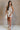 Full body view of female model wearing the Elodie Beige Ruffle Tier Sleeveless Romper which features Beige Lightweight Fabric, Beige Lining, Ruffle Tier Details, Round Neckline, Sleeveless and Back Button Closure