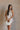Front view of female model wearing the Elodie Beige Ruffle Tier Sleeveless Romper which features Beige Lightweight Fabric, Beige Lining, Ruffle Tier Details, Round Neckline, Sleeveless and Back Button Closure