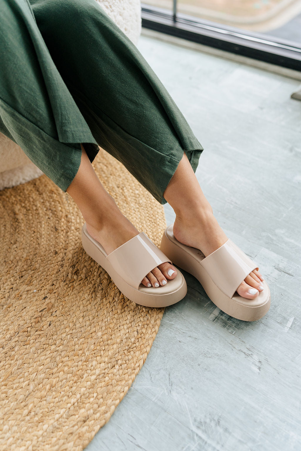 Front angle view of female model wearing the Solar Sandal in Nude which features Faux patent leather upper Slide style sandal for an easy on and off Lightly padded footbed Platform midsole.