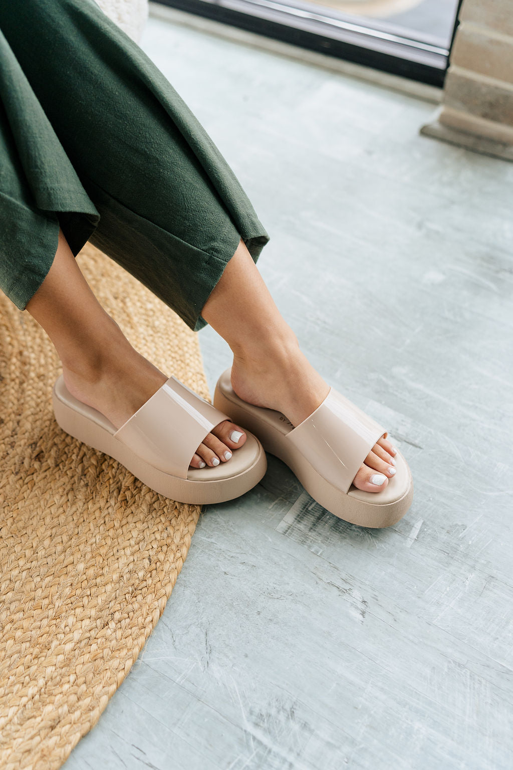 Front angle view of female model wearing the Solar Sandal in Nude which features Faux patent leather upper Slide style sandal for an easy on and off Lightly padded footbed Platform midsole.