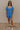 Front view of model wearing the Marissa Blue and White Floral Short Sleeve Romper which features Blue Lightweight Fabric, White Floral Design, Blue Lining, Square Neckline, Short Puff Sleeves and Smocked Back.