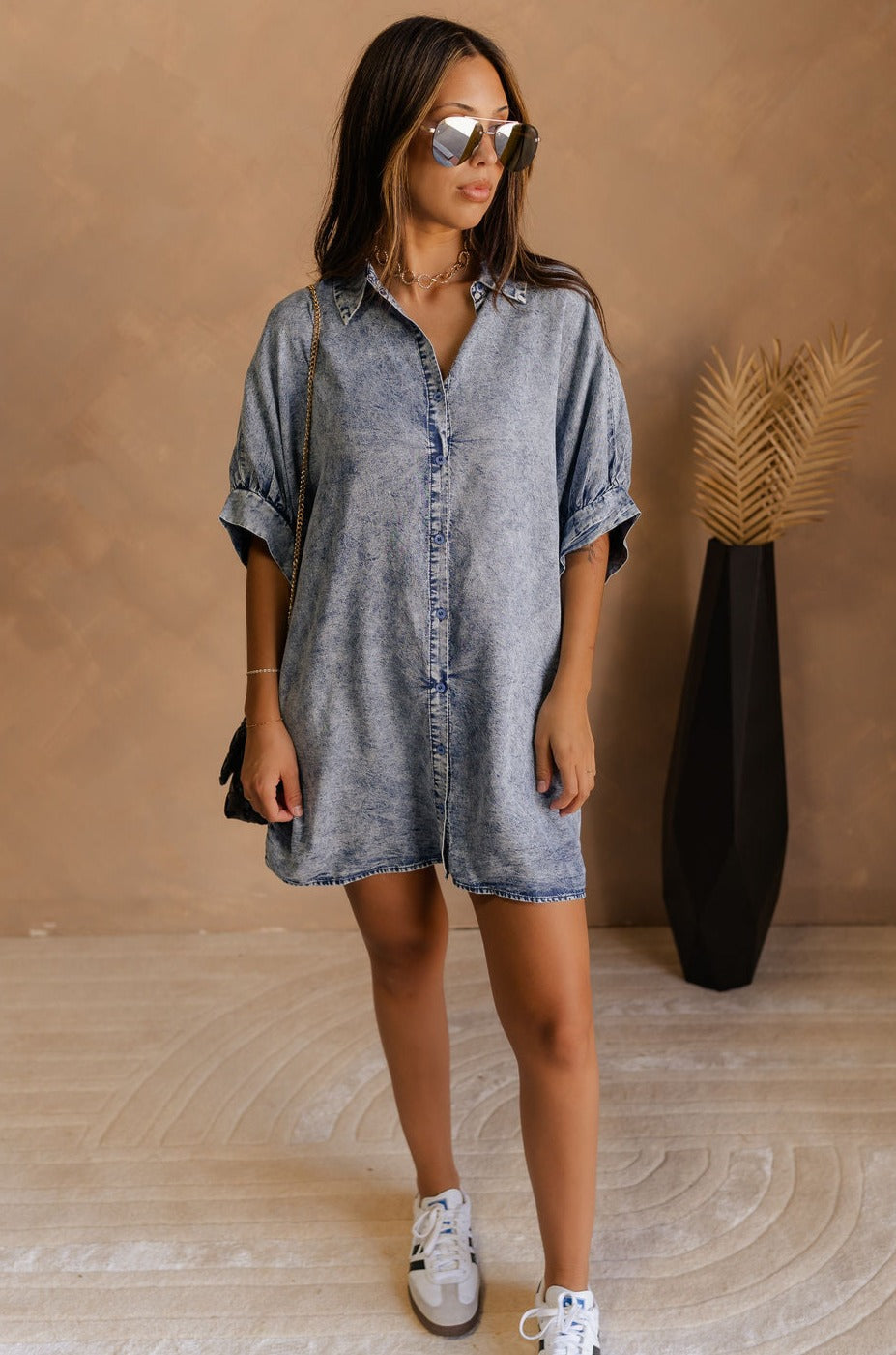 Full body view of female model wearing the  Emma Button-Up Short Sleeve Mini Dress in Washed Denim which features  Tencel Fabric, Mini Length, Front Button-Up Closure, Collared Neckline and  Short Puff Sleeves.