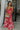 Full body front view of model wearing the Roselyn Pink & Red Floral Maxi Dress that has light pink fabric with dark pink and red floral pattern, a cowl neckline, and spaghetti straps that cross in the back.