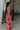 Full body side view of model wearing the Roselyn Pink & Red Floral Maxi Dress that has light pink fabric with dark pink and red floral pattern, a cowl neckline, and spaghetti straps that cross in the back.