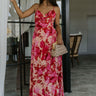 Full body front view of model wearing the Roselyn Pink & Red Floral Maxi Dress that has light pink fabric with dark pink and red floral pattern, a cowl neckline, and spaghetti straps that cross in the back.