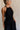 Side view of female model wearing the Luna Halter Tie Tiered Maxi Dress in black which features Lightweight Fabric, Tiered Body, Maxi Length, Thigh Length Lining, Halter Neckline with Tie and Open Back