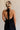 Back view of female model wearing the Luna Halter Tie Tiered Maxi Dress in black which features Lightweight Fabric, Tiered Body, Maxi Length, Thigh Length Lining, Halter Neckline with Tie and Open Back