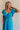 Front view of female model wearing the Gianna Ruffle Short Sleeve Tiered Maxi Dress in Blue which features Lightweight Fabric, Tiered Body, Midi Length, Pockets on each side, V-Neckline with a Tie Detail and Ruffle Short Sleeves. the dress is available in pink, aqua blue and white.
