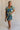 Full body view of female model wearing the Tessa Blue & Lime Green Floral Mini Dress which features Blue, Green and White Light Weight Fabric, Floral Print, Mini Length, Tiered Body, Blue Lining, V-Neckline and Short Puff Sleeves