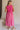 Full body back view of female model wearing the Cecilia Pink Smocked Midi Dress which features Pink Lightweight Fabric, Pink Lining, Pockets On Each Side, Midi Length, Textured Upper, Square Neckline and Sleeveless