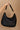 Hand is shown holding the Sabrina Braided Shoulder Tote in Black that has a woven body, top zipper, and a braided shoulder strap.