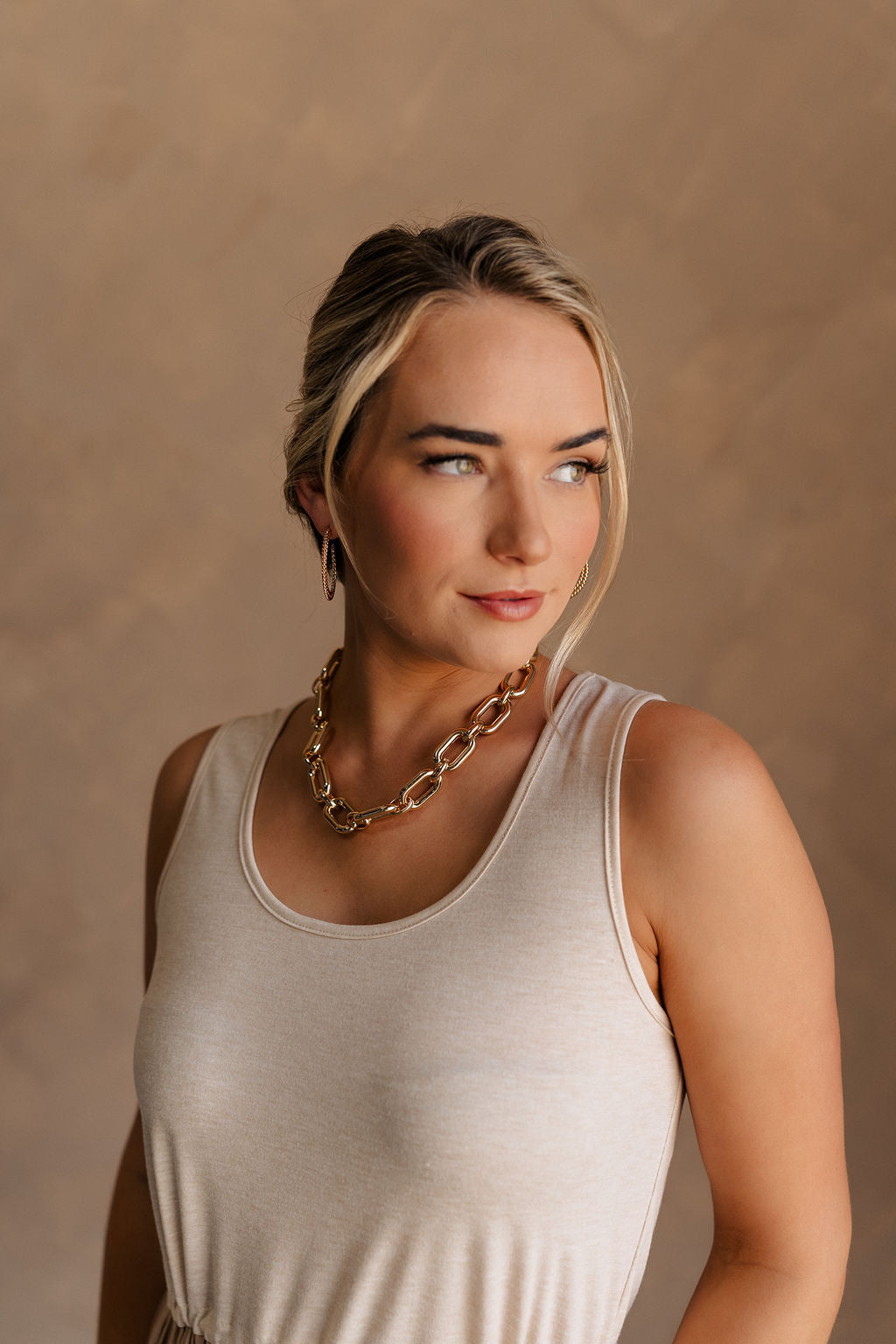 Front view of female model wearing the Celeste Gold Chain Link Necklace which features shiny gold, chunky chain links linked together with an adjustable clasp closure. 