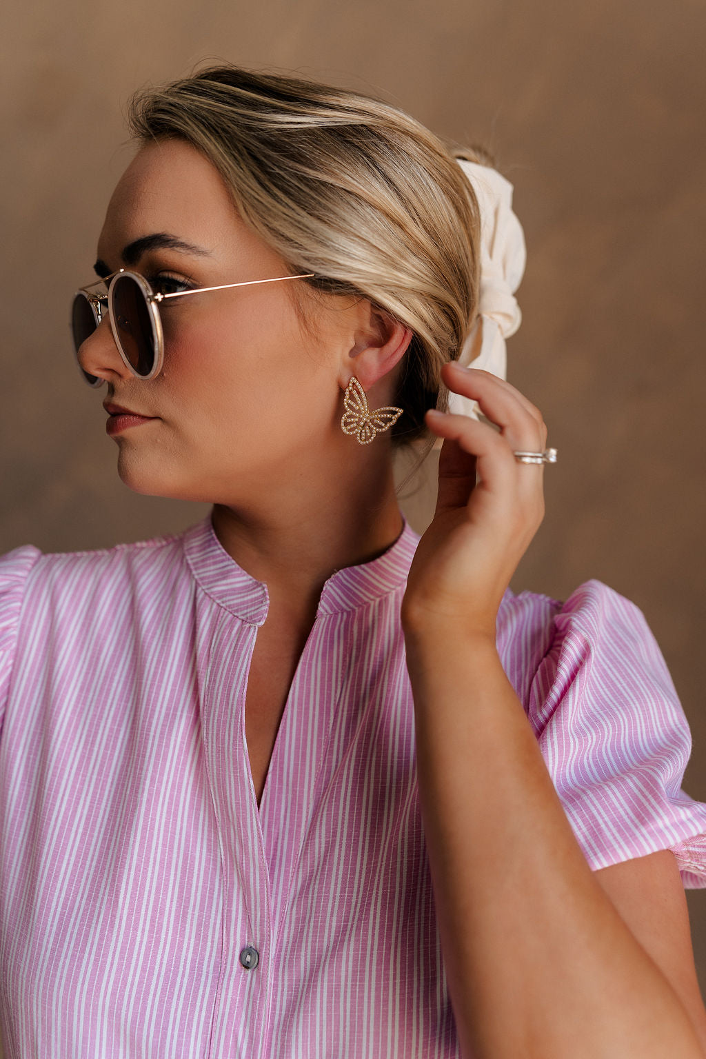Side view of female model wearing the Emma Pearl & Gold Butterfly Stud Earring which features butterfly oversized shaped studs, pearl and gold detail and with a back closure