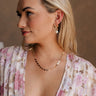 Side view of female model wearing the Mina Gold Floral & Pearl Dangle Earring which features gold flower shaped stud linked with a pearl dangle medallion