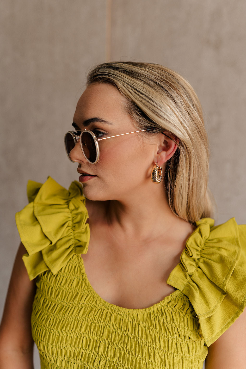 Side view of female model wearing the Athena Gold Ribbed Scooped Hoop Earring which features gold ribbed scooped hoop earring with back closure