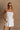 Upper body front view of female model wearing the Kelsey White Denim Romper that has white denim fabric, a strapless neck, and a pleated skirt over shorts lining.