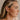 Side view of female model's face; model is wearing the Aubriella Raffia Lantern Earrings that have tan raffia balls dangling.