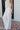 Side view of female model wearing the Alice Off White Wide Leg Drawstring Pants which features Off White Lightweight Linen Fabric, Off White Lining, Wide Pant Legs, Side Pockets and Elastic Waistband with Drawstring Tie