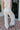 Back view of female model wearing the Alice Off White Wide Leg Drawstring Pants which features Off White Lightweight Linen Fabric, Off White Lining, Wide Pant Legs, Side Pockets and Elastic Waistband with Drawstring Tie