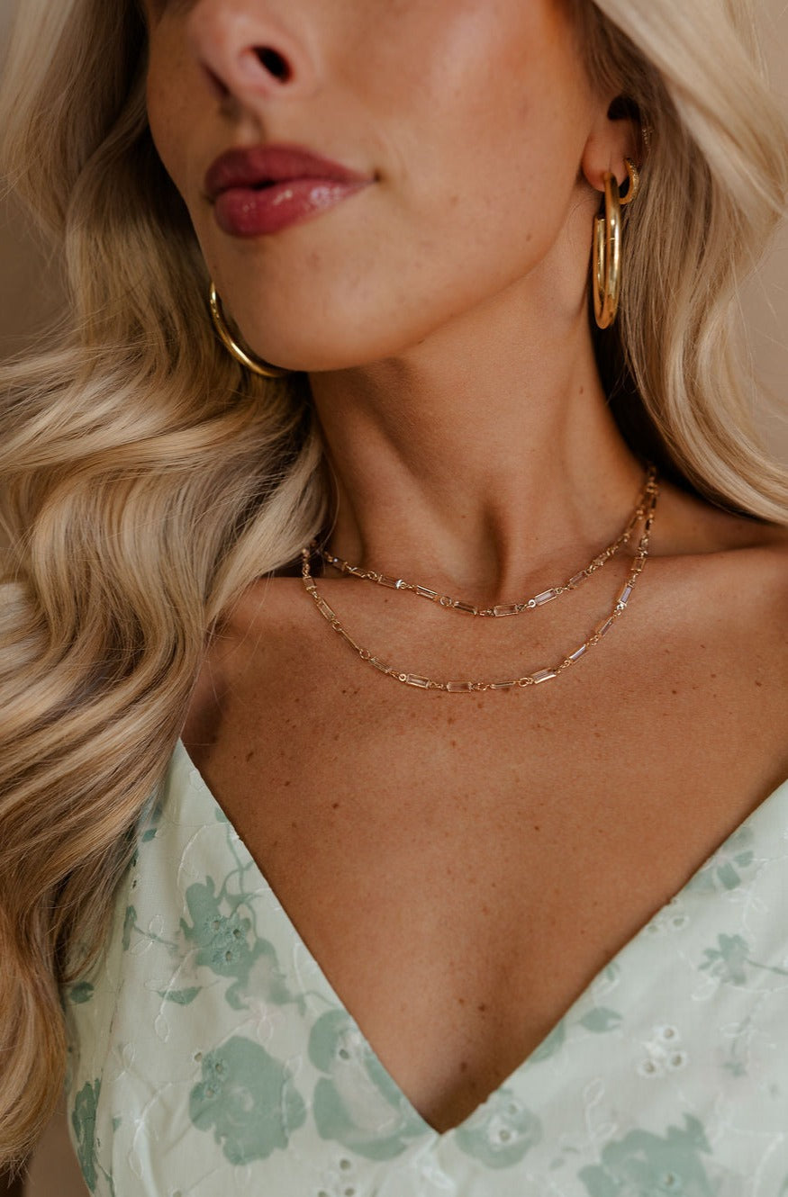 A close-up of model's neck is shown. She is wearing the Magdelene Necklace in Crystal.