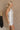 Side view of female model wearing the Isla White Silver Ruched Halter Neckline Mini Dress which features White Silver Fabric, White Lining, Ruched Details, Overlap Hem, Halter Neckline and Monochrome Back Zipper with Hook Closure