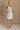 Full body back view of female model wearing the Isla White Silver Ruched Halter Neckline Mini Dress which features White Silver Fabric, White Lining, Ruched Details, Overlap Hem, Halter Neckline and Monochrome Back Zipper with Hook Closure