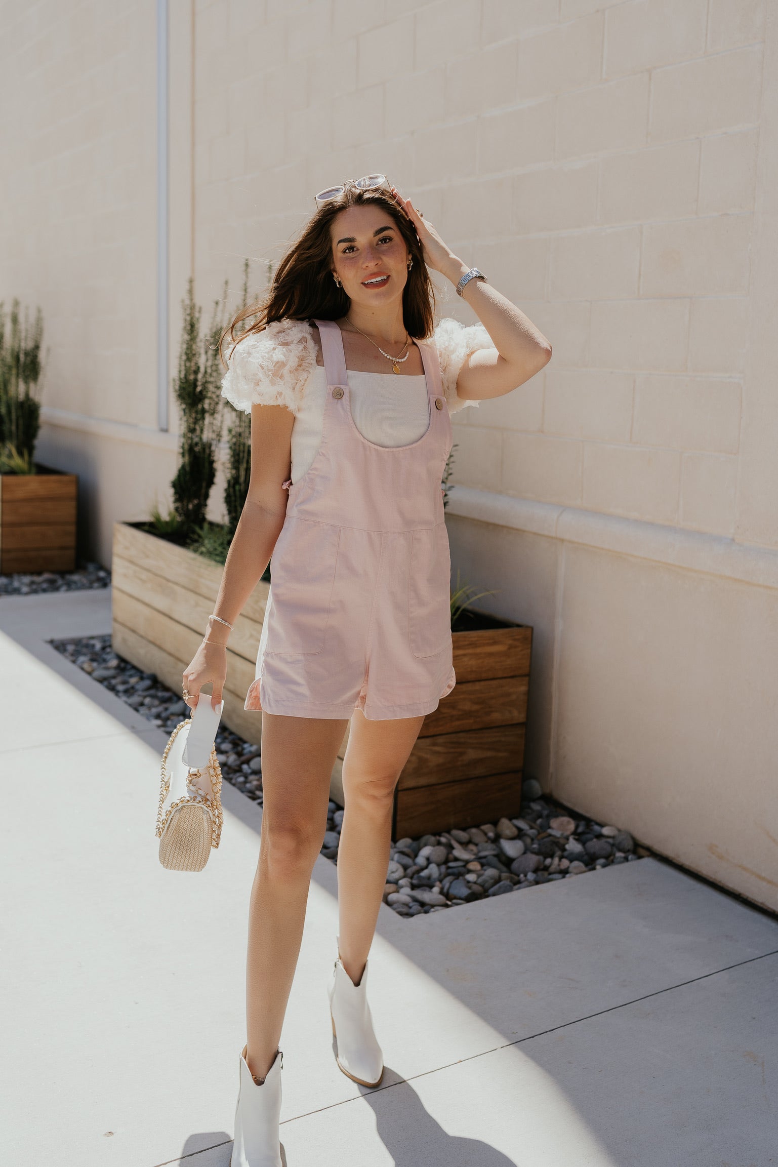 image of model wearing a pink romper with white puffy sleeve top, white button links to rompers & reads "shop rompers"