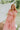 Full body view of female model wearing the Allie Coral Pink Ruffle Midi Dress which features Coral Pink Lightweight Fabric, Midi Length, Coral Pink Lining, Ruffle Tier Skirt, Smocked Upper, Square Neckline, Ruffle Straps and Two Side Pockets