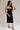 Full body view of female model wearing the Marissa Black & White Trim Midi Dress which features Black Lightweight Fabric, Midi Length, Black Lining, White Trim Details, Back Slit , Square Necklineand Side Monochrome Zipper with Hook Closure