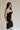 side view of female model wearing the Marissa Black & White Trim Midi Dress which features Black Lightweight Fabric, Midi Length, Black Lining, White Trim Details, Back Slit , Square Necklineand Side Monochrome Zipper with Hook Closure