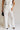 fronnt view of female model wearing the Amelia Off White & Black Wide Leg Pants which features Off White Linen Fabric, Black Trim Details, Front Pockets, Wide Pant Legs, Front Zipper with Tortoise Button Closure and Belt Loops