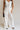 front view of female model wearing the Amelia Off White & Black Wide Leg Pants which features Off White Linen Fabric, Black Trim Details, Front Pockets, Wide Pant Legs, Front Zipper with Tortoise Button Closure and Belt Loops