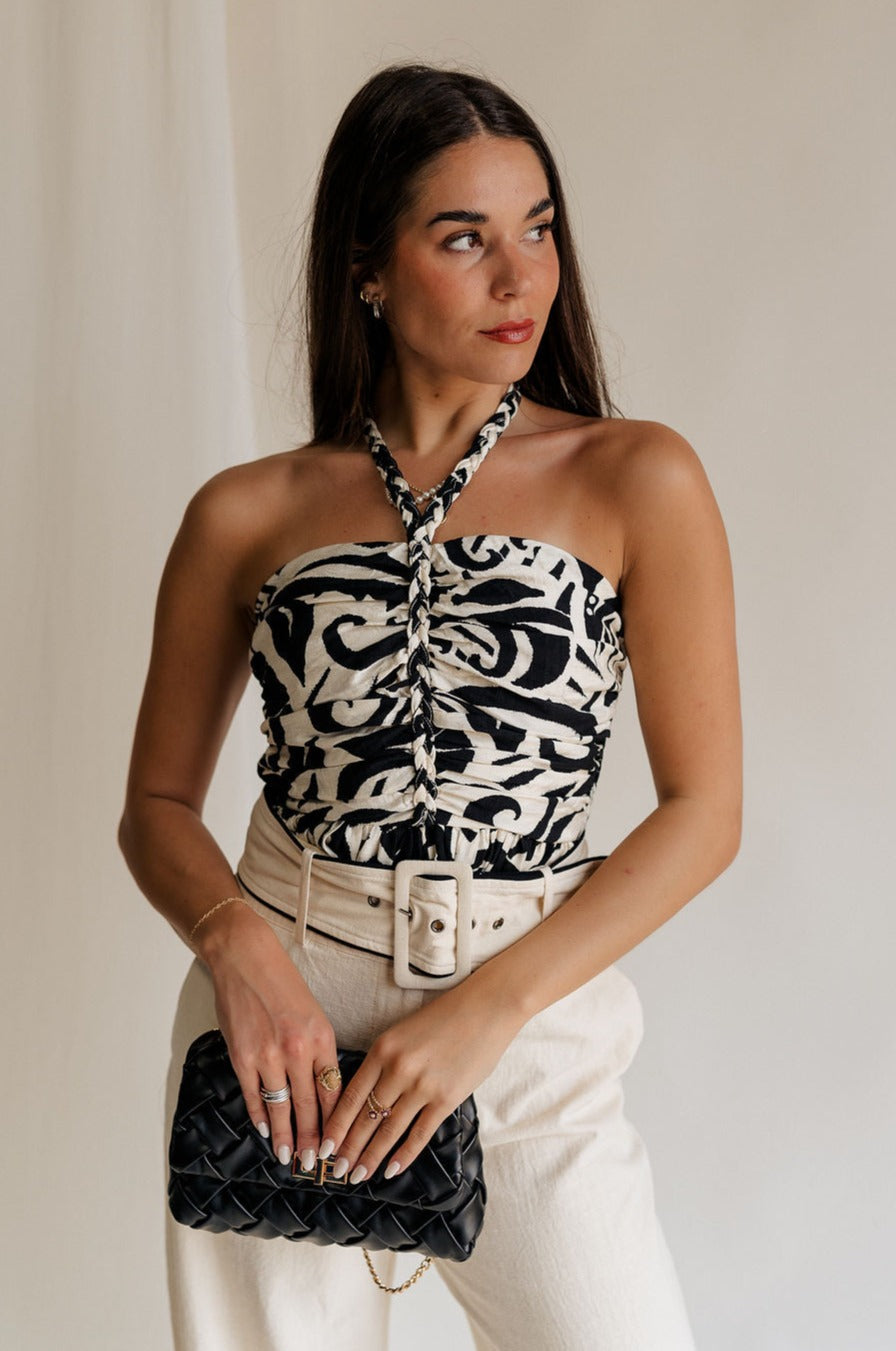 front view of female model wearing the Olivia Black & White Swirl Braided Halter Tank which features Black and Cream Floral Fabric, Peplum Body, Ruched Upper, Braided Halter Neckline and Smocked Back