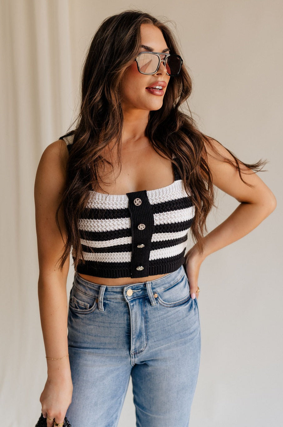 front view of female model wearing the Kai Black & White Stripe Knit Tank which features Black and White Crochet Knit, Stripe Pattern, Cropped Waist, Rhinestone Button Up, Square Neckline and Sleeveless