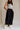Lower body front view of female model wearing the Meredith Black Cropped Wide Leg Pants that have black fabric, cropped wide legs, side slits, and a drawstring waist.