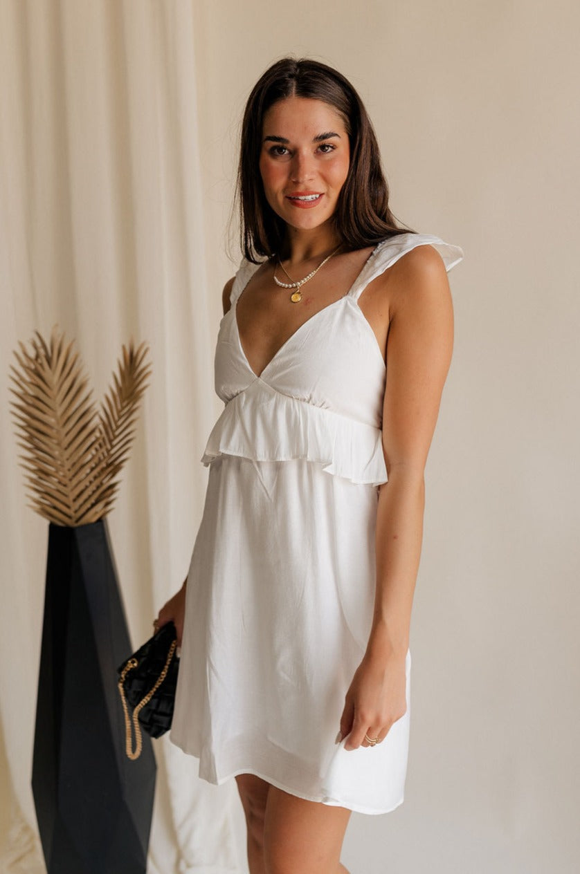 front view of female model wearing the Noelle White Ruffle Plunge Neckline Mini Dress which features White Lightweight Fabric, White Lining, Mini Length, Ruffle Details, V-Neckline and Smocked Back