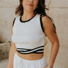 Front view of female model wearing the Lucia White & Black Groovy Hem Tank which features White Ribbed Fabric, Cropped Tank, Black Intertwine Hem Detail, Round Neckline and Sleeveless