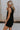Side view of female model wearing the Athena Front Zip-Up Halter Romper which features Denim Like Fabric, Pockets on each side, Two Back Pockets, Folded Hem Details, Front Zipper Closure, Collared Neckline and Sleeveless. the romper is available in red and black