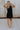 Full body back  view of female model wearing the Athena Front Zip-Up Halter Romper which features Denim Like Fabric, Pockets on each side, Two Back Pockets, Folded Hem Details, Front Zipper Closure, Collared Neckline and Sleeveless. the romper is available in red and black