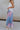 Side view of female model wearing the Lily Aqua & Pink Multi Pleated Maxi Skirt which features Blue, Pink, Red, Purple and Aqua Floral Print, Satin Pleated Fabric, Maxi Length, Light Blue Lining and Side Zipper with Hook Closure