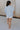 Full body back view of female model wearing the Noelle Chambray Blue Short Sleeve Top which features Light Blue Cotton Fabric, Slight Cropped Waist, Short Puff Sleeves and V-Neckline