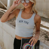 front view of female model wearing the New York Grey & Navy Graphic Tank which features Light Grey Knit Fabric, Cropped Waist, Square Neckline, Sleeveless and NEW YORK in navy block stitch letters