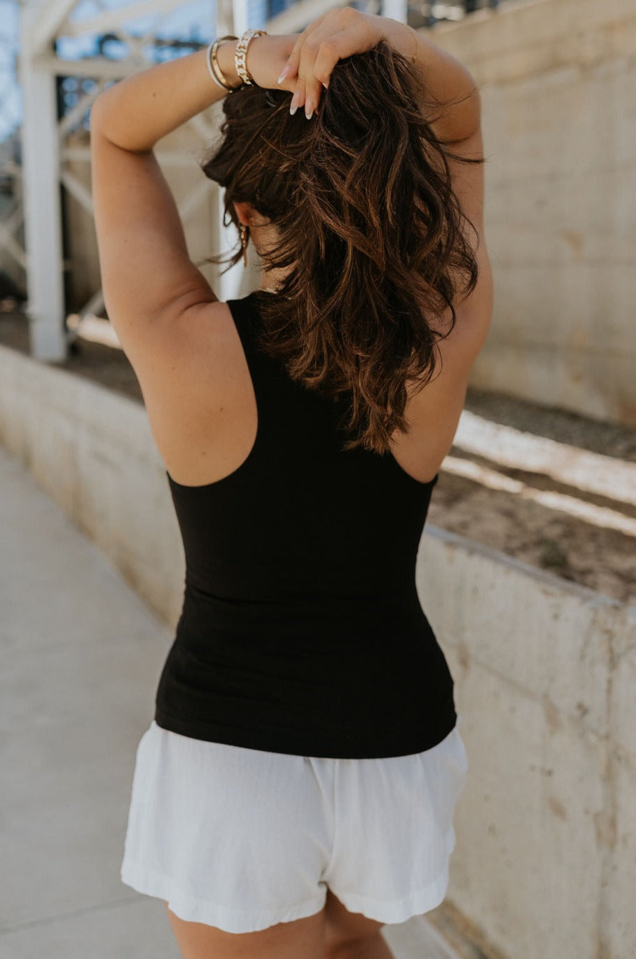 back view of female model wearing the Lianna Black Sleeveless Tank which features Black Lightweight Fabric, Black Lining, Round Neckline and Sleeveless