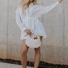 Full body view of female model wearing the Laura Off White Drawstring Cinched Long Sleeve Top which features Off White Lightweight Fabric, Slit Hem Details, Front Button-Up, Adjustable Cinch Waistband,  Collared Neckline and Long Sleeves with Buttoned Cuffs