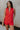 Front view of female model wearing the Athena Front Zip-Up Halter Romper which features Denim Like Fabric, Pockets on each side, Two Back Pockets, Folded Hem Details, Front Zipper Closure, Collared Neckline and Sleeveless. the romper is available in red and black