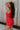 Side view of female model wearing the Athena Front Zip-Up Halter Romper which features Denim Like Fabric, Pockets on each side, Two Back Pockets, Folded Hem Details, Front Zipper Closure, Collared Neckline and Sleeveless. the romper is available in red and black