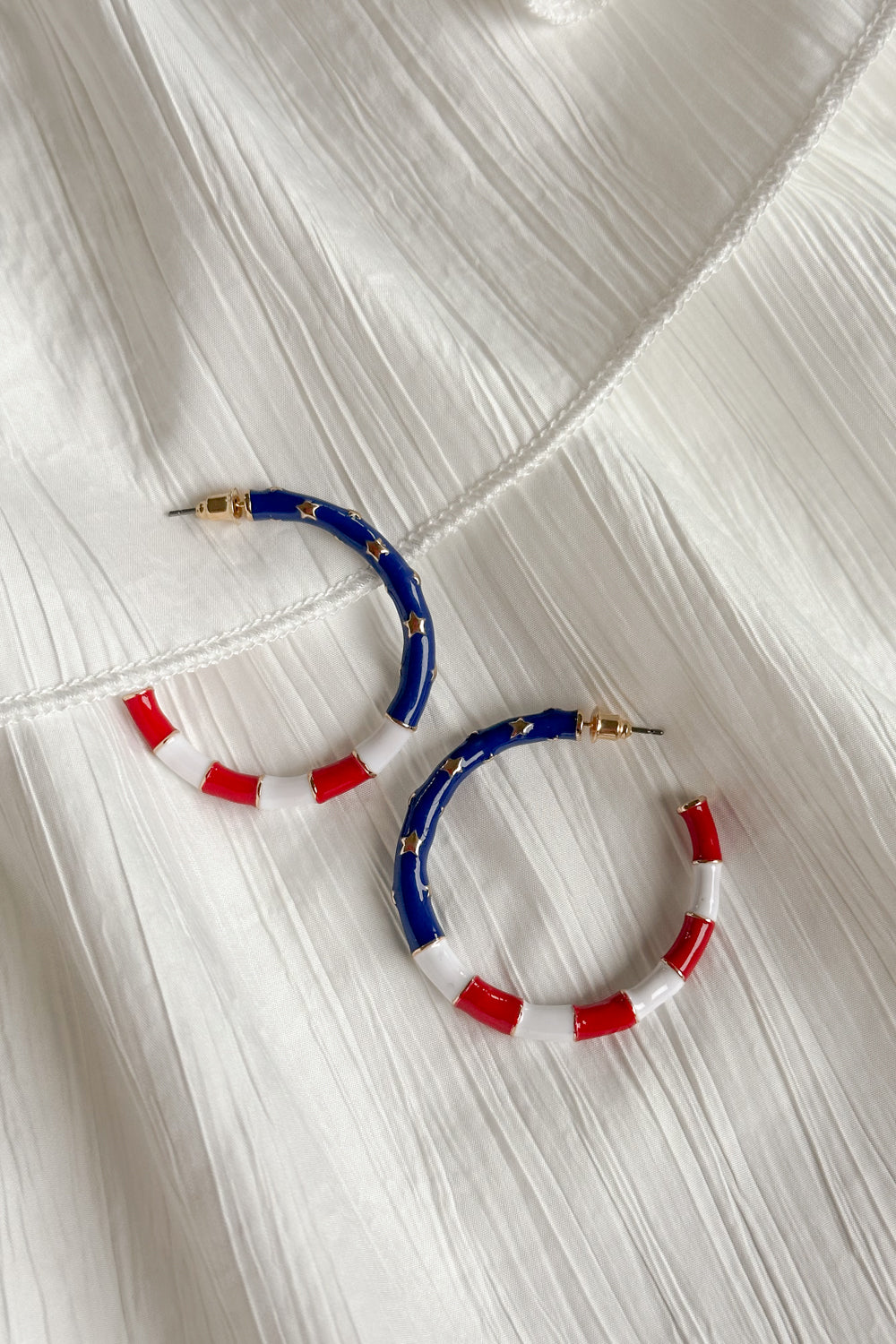 Image shows Eleanor Red, White, & Blue Hoop Earrings against a white background. Earrings feature red and white striped and a blue section with gold stars.