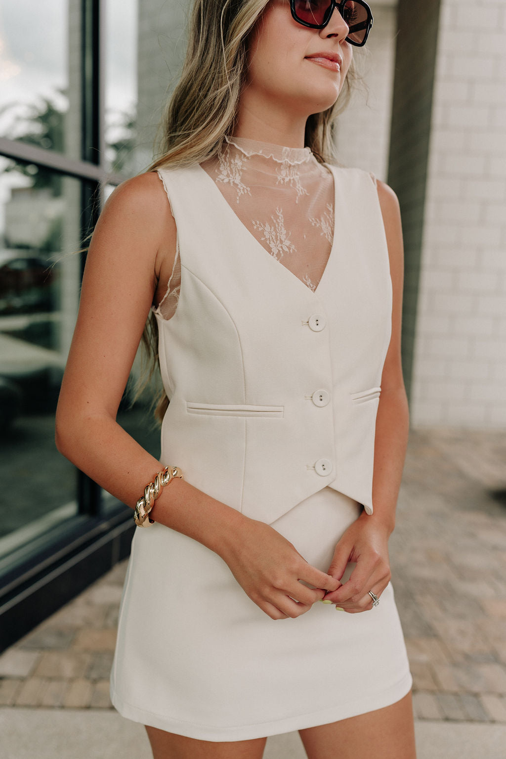 Front view of female model wearing the Isabella Cream Button-Up Vest which features Cream Lightweight Fabric, Cropped Waist, Monochrome Button Up, V-Neckline and Sleeveless